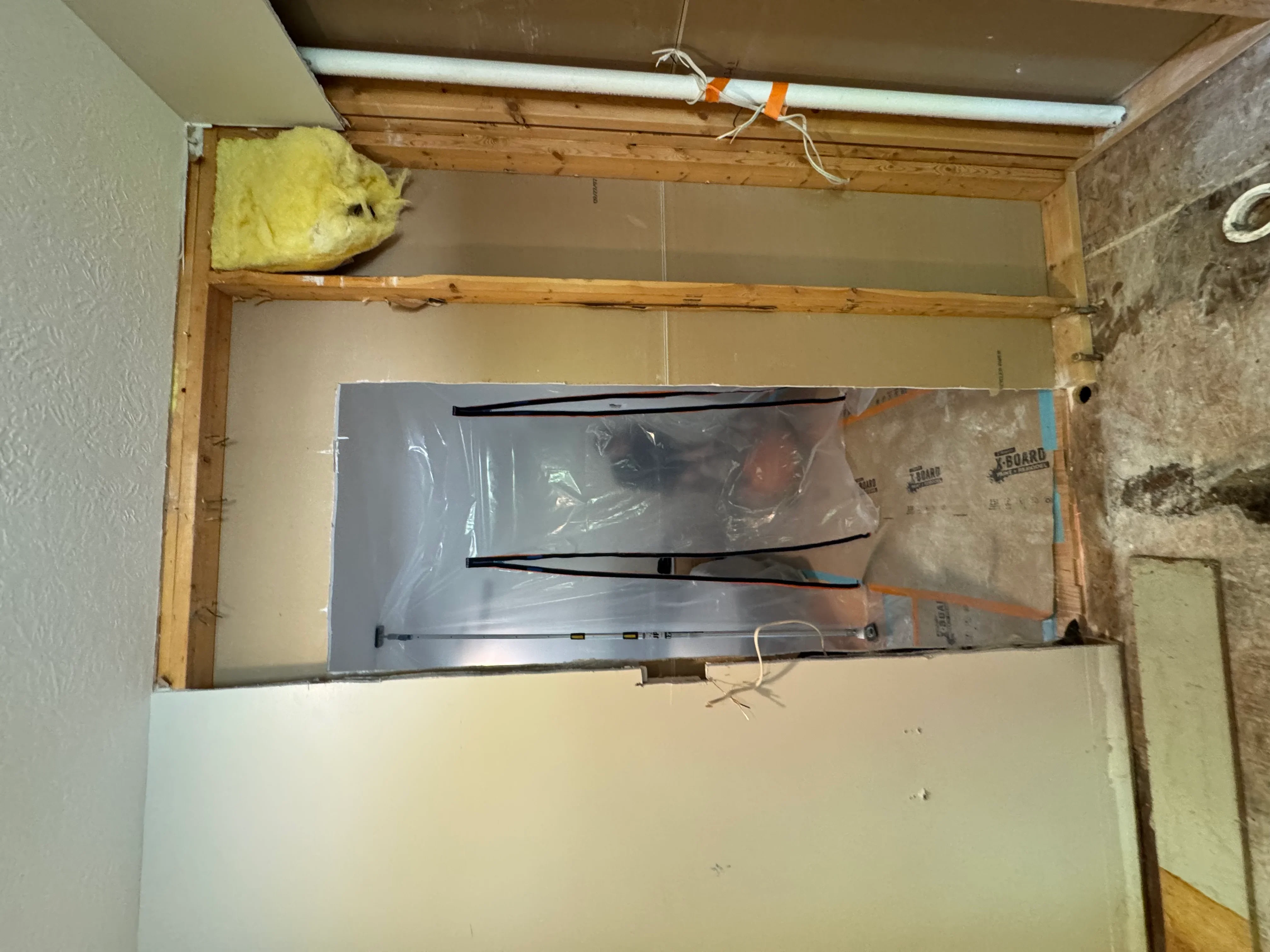 HVAC unit installation with wood framing, fiberglass insulation, and drywall in progress