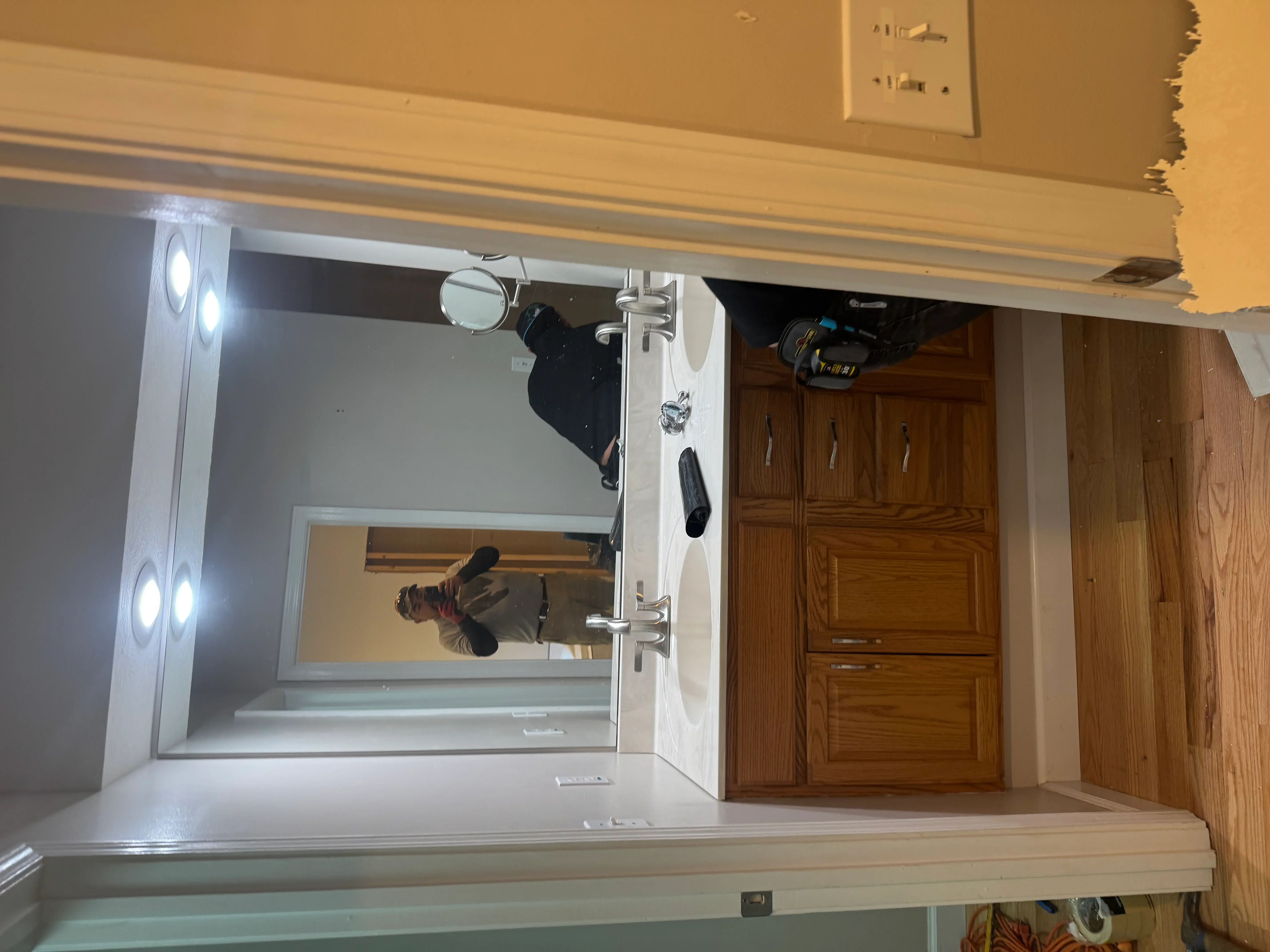 White bathroom vanity with dual LED mirror sconces and chrome faucet installation