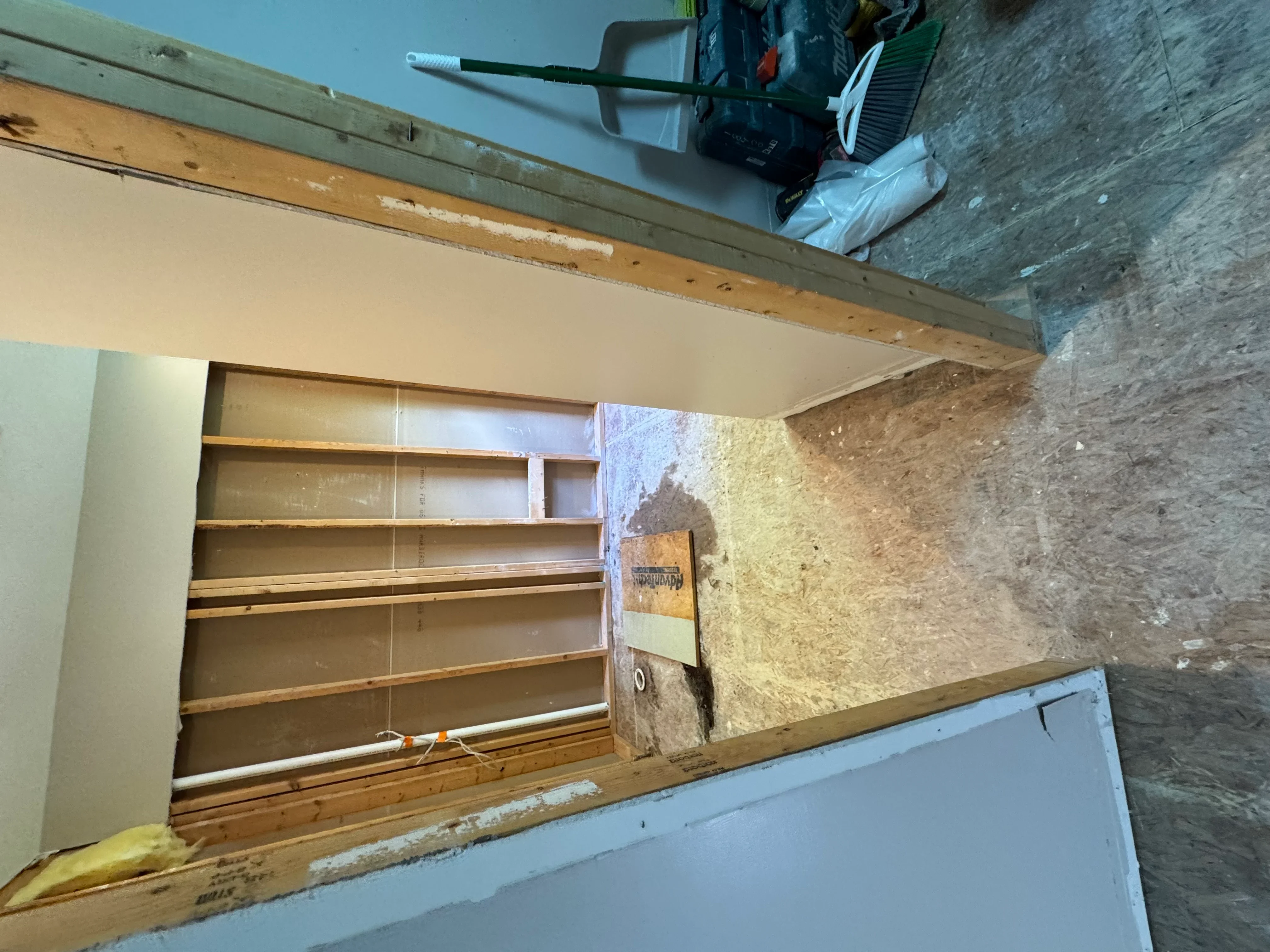 Wooden stud framing with drywall installation, horizontal and vertical structural supports visible
