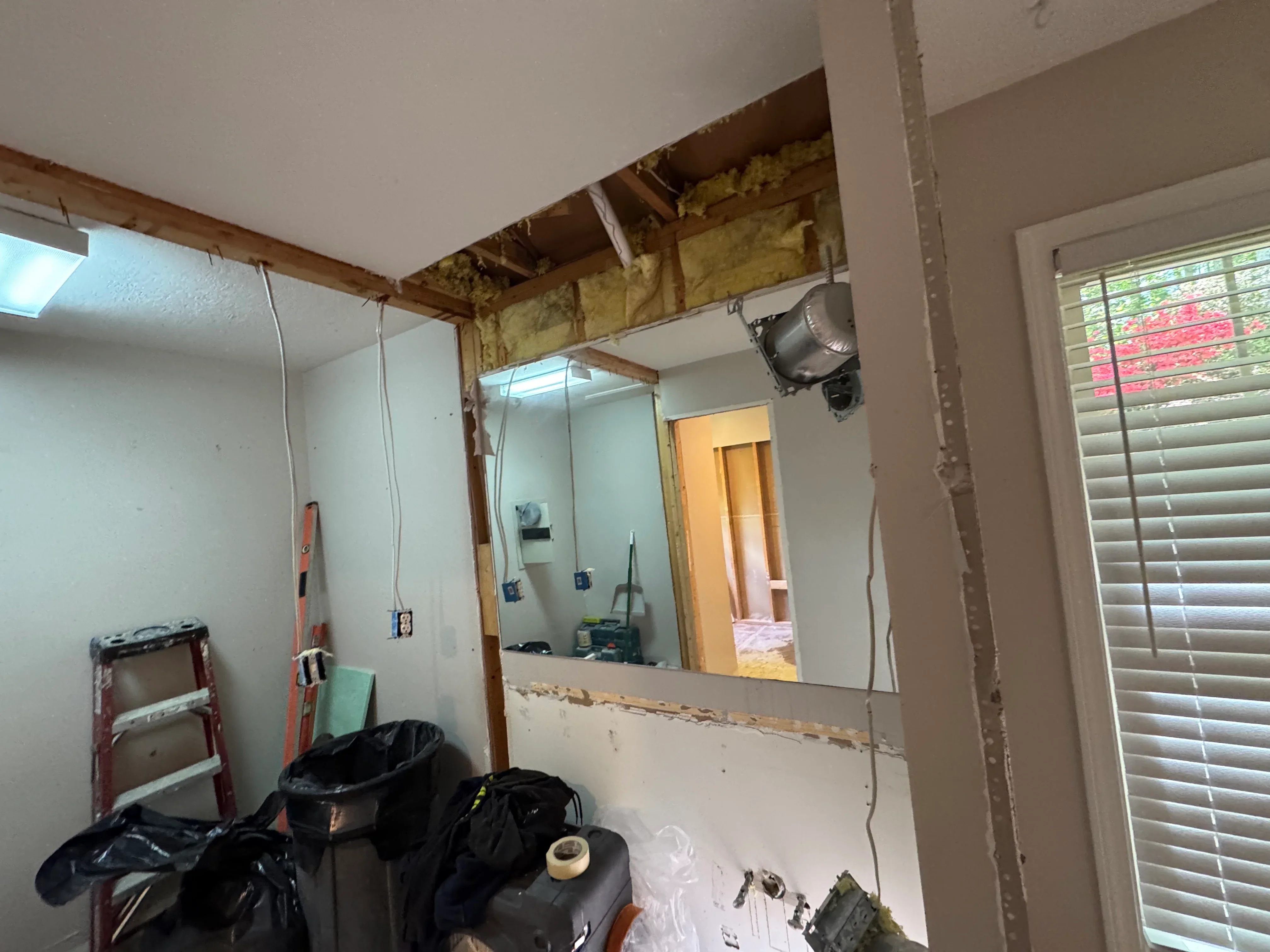 Bathroom under renovation with new drywall, wooden framing, and electrical wiring installation