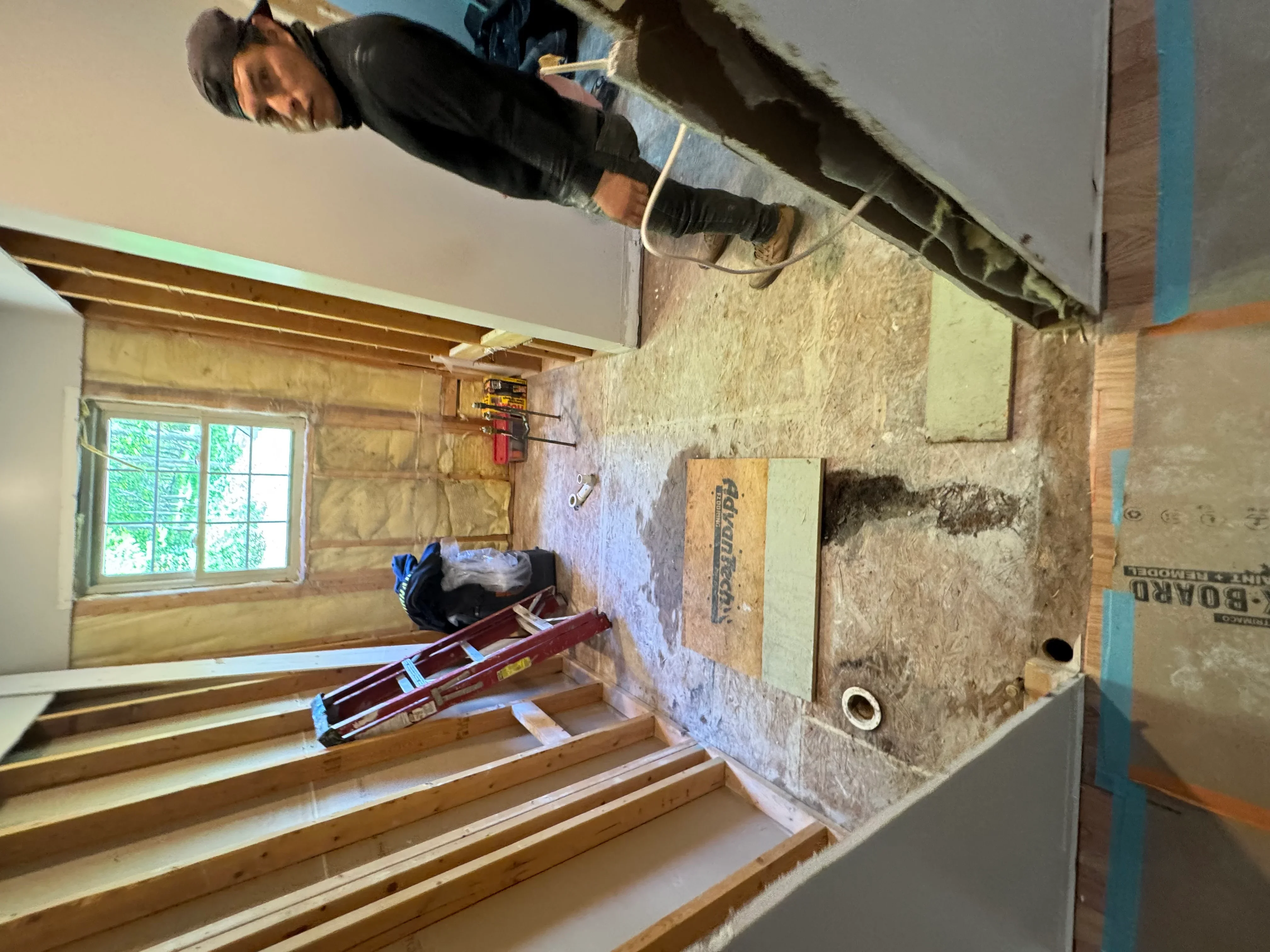 Interior framing with wood studs, fiberglass insulation, and drywall installation in progress