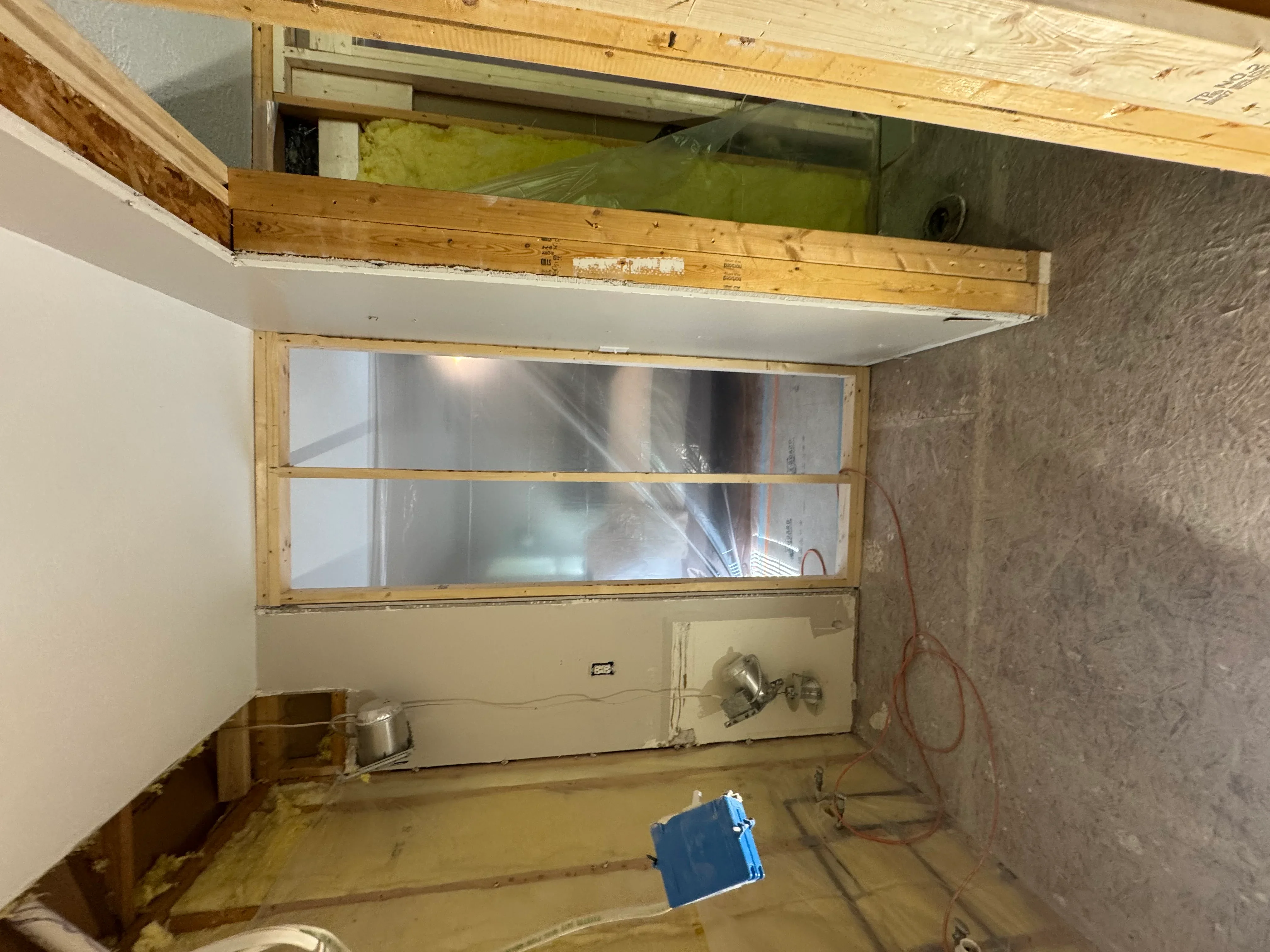 Kitchen soffit framing with new window installation, drywall, and wood trim during renovation