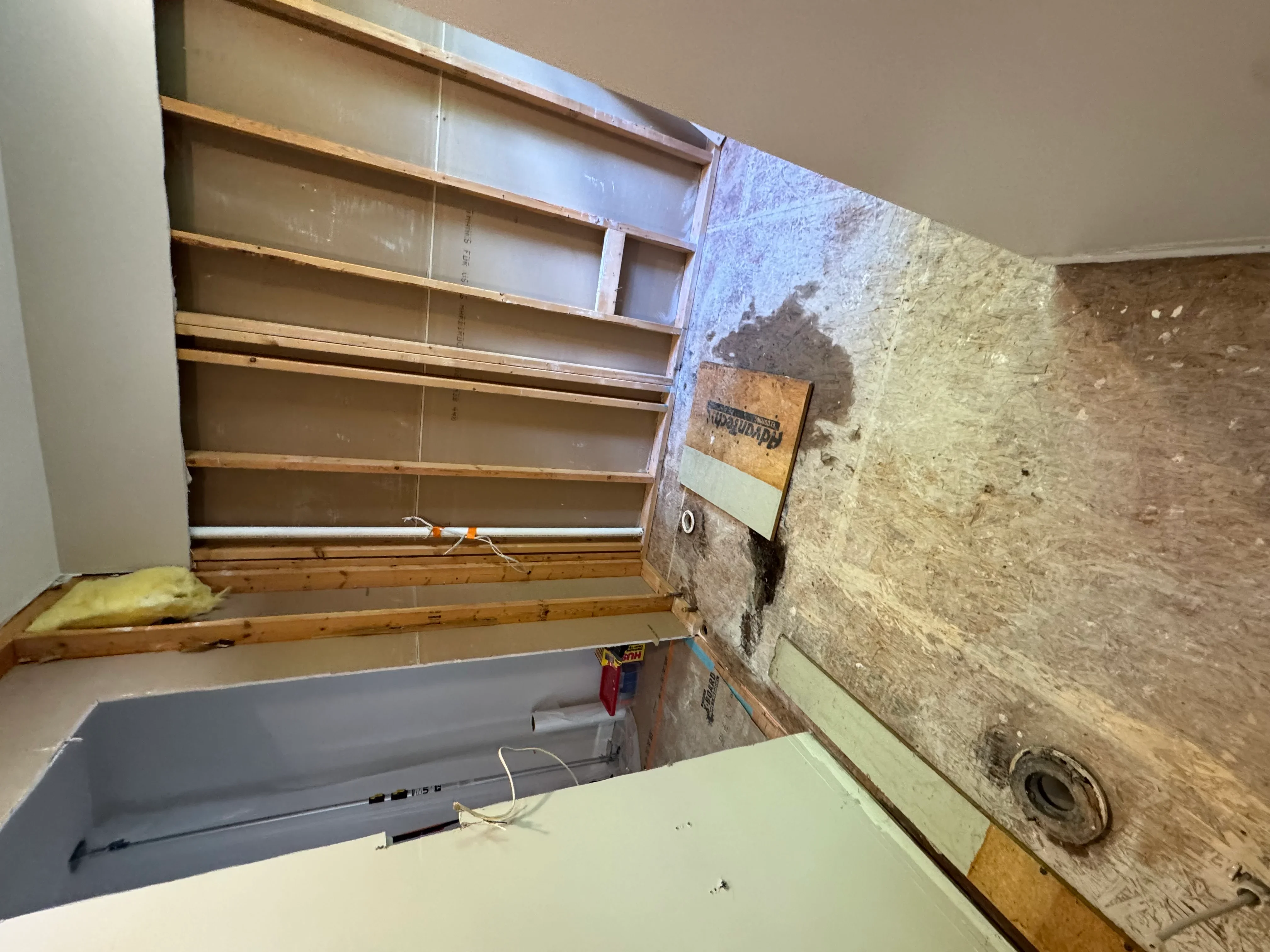 Basement wall framing with fiberglass insulation batts between wooden studs and vapor barrier