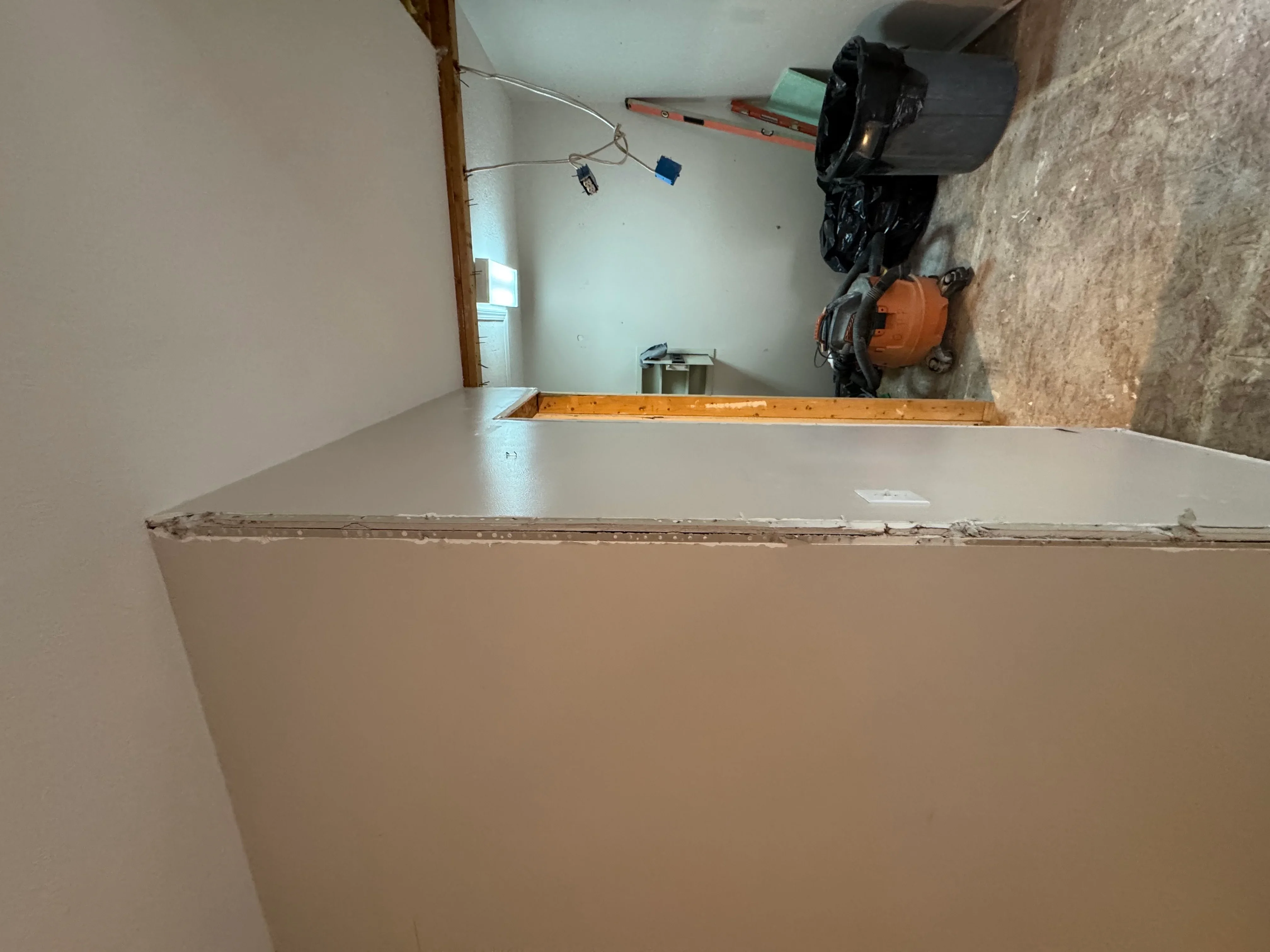 Drywall installation with taped seams and electrical rough-in in basement space